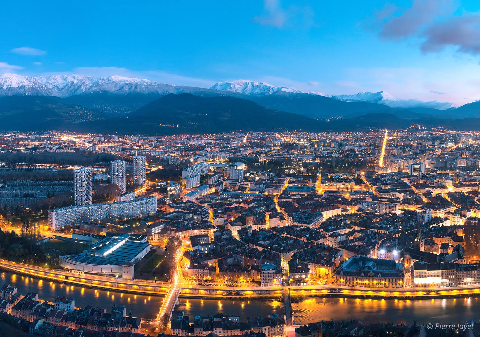 Grenoble illuminée au crépuscule, au pied des montagnes